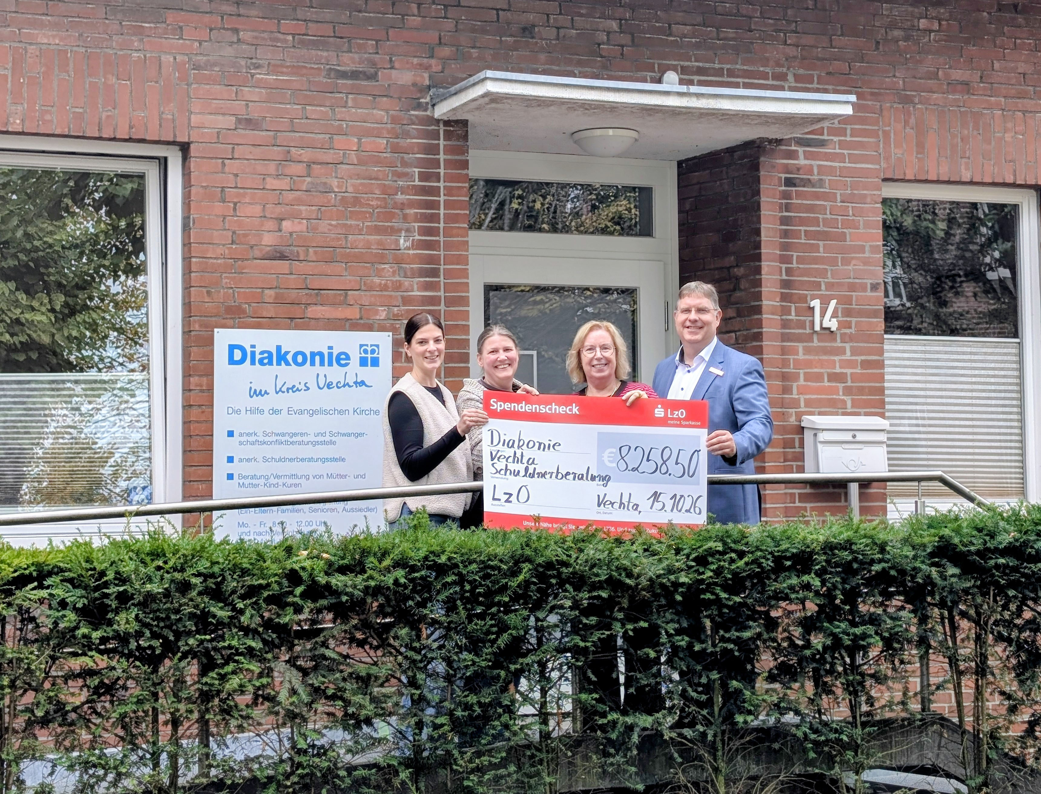 Andrea Tegenkamp und Angela Müller, Schuldnerberaterinnen, Martina Fisser, Geschäftsleitung des Diakonischen Werks Vechta, und Ingo Ruhe von der LzO stehen vor dem Gebäude des Diakonischen Werks und halten gemeinsam einen Spendenscheck über 8.258,50 Euro.
